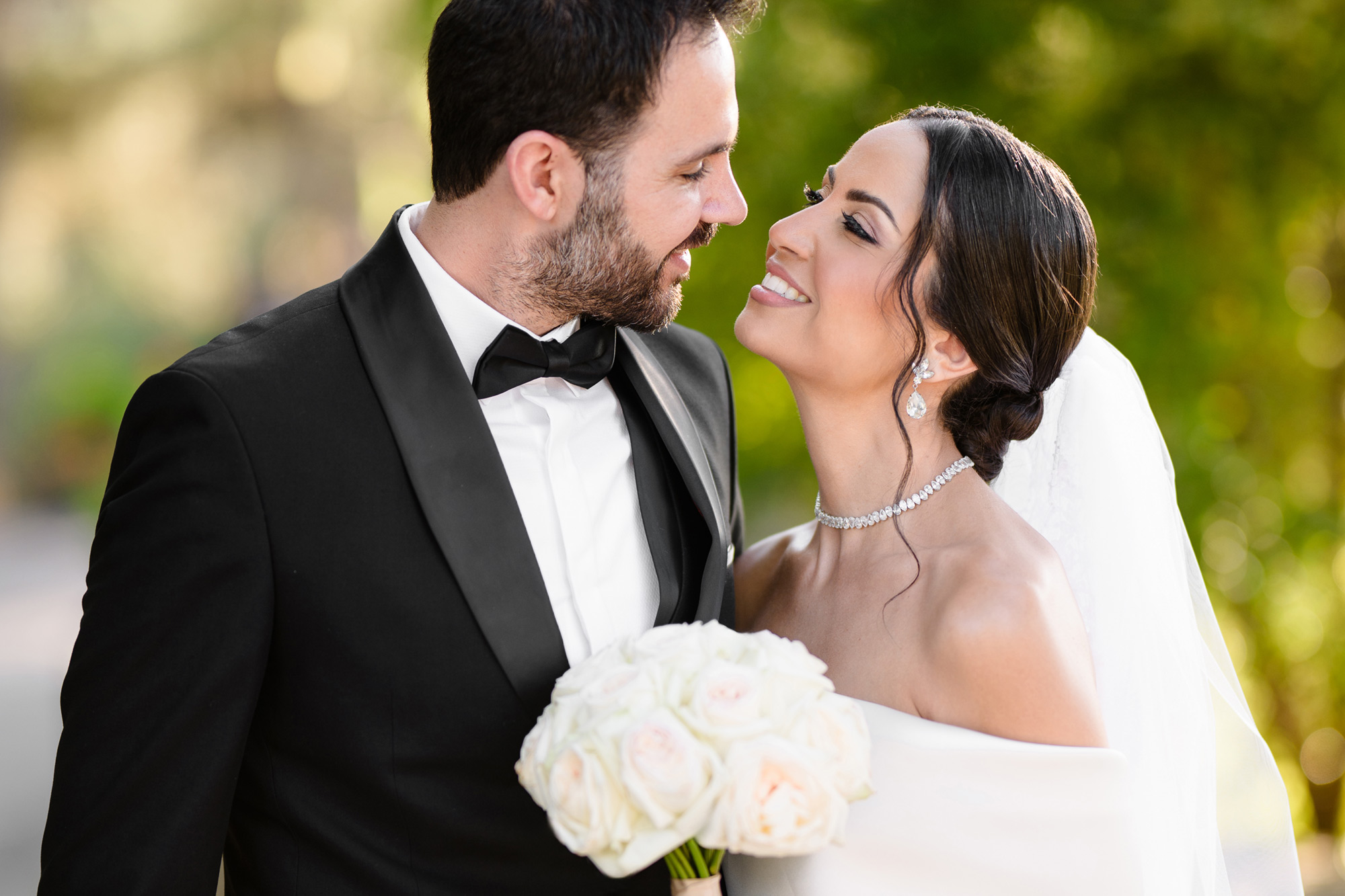 luxury bride with white bouquet and groom in black tuxedo